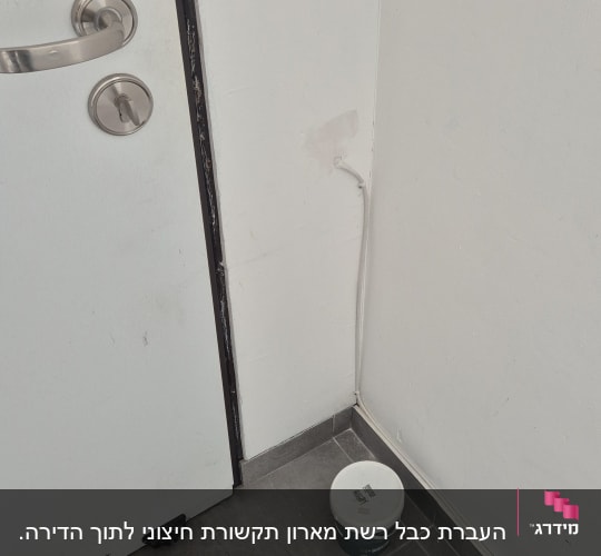 כבל לבן מחובר לקיר ליד דלת